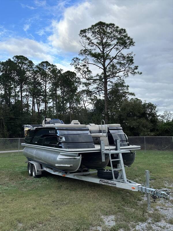 Black pontoon boat on a trailer in the yard