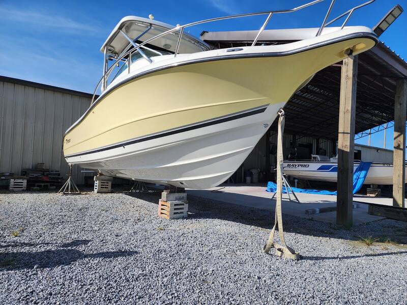 Yellow-hulled cabin boat on stands outside the shop